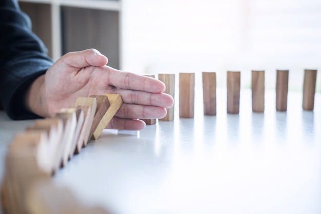 Foto rischio e strategia nel mondo degli affari, immagine della mano che interrompe la caduta crollo del blocco in legno effetto domino da blocco rovesciato continuo, prevenzione e sviluppo alla stabilità