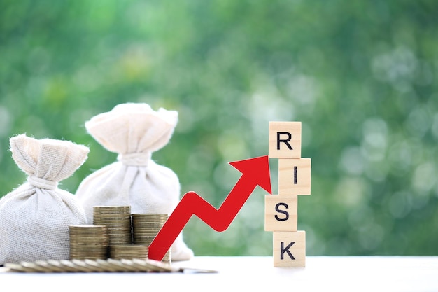 Фото Слово риска с графиком с красной стрелкой и мешком с деньгами на естественном зеленом фоне бизнес-инвестиции и концепция управления рисками оценка финансового риска