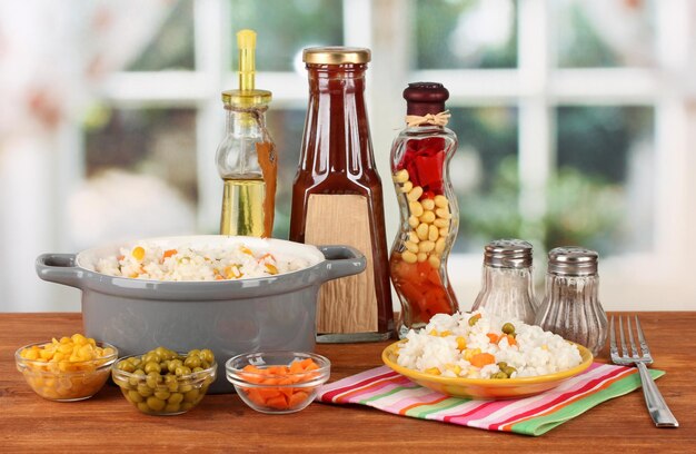 Risotto in gray pot on wooden table on bright background