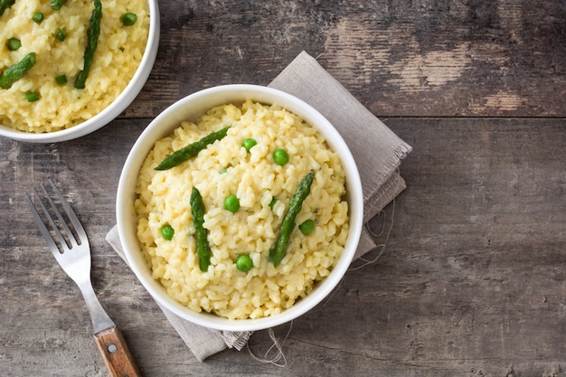 Risotto met asperge peterselie en erwten in een kom op een rustieke houten tafelblad bekijken