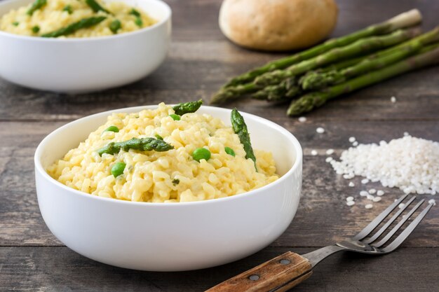 Risotto met asperge peterselie en erwten op een rustieke houten tafel