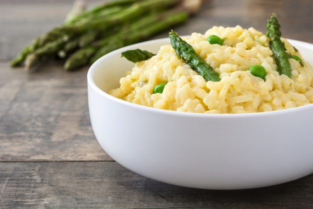 Risotto met asperge peterselie en erwten op een rustieke houten tafel