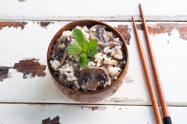 Risotto met champignons op een houten plaat en eetstokjes