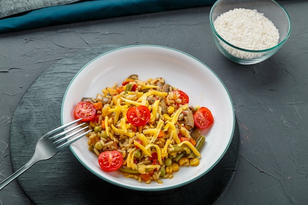 Risotto met rundvlees en kaas in een bord op een grijze ondergrond op een zwart bord naast een vork