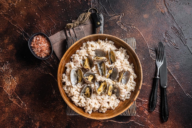 Risotto met venusschelpen en zeevruchten in een houten plaat. donkere achtergrondgeluid. bovenaanzicht.