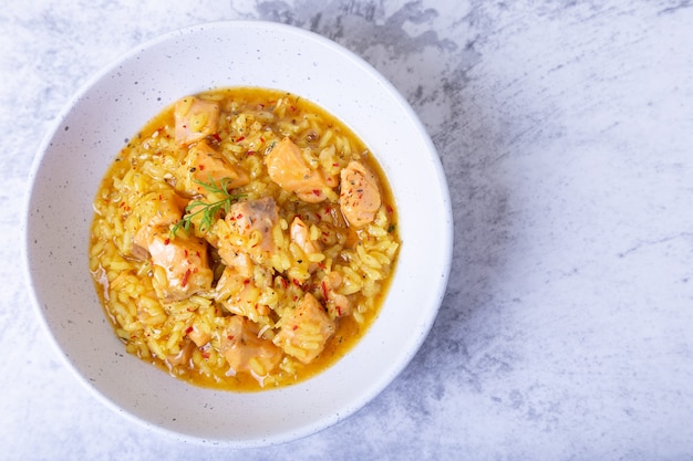 Risotto met zalm en saffraan in een witte plaat. Traditionele Italiaanse keuken. Close-up, bovenaanzicht.