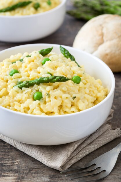 Risotto with asparagus parsley and peas in a bowl on a rustic wooden table