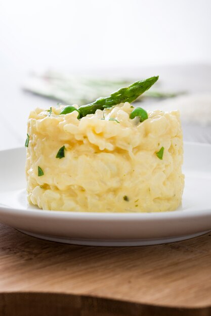 Risotto with asparagus, parsley and peas on a rustic wooden table