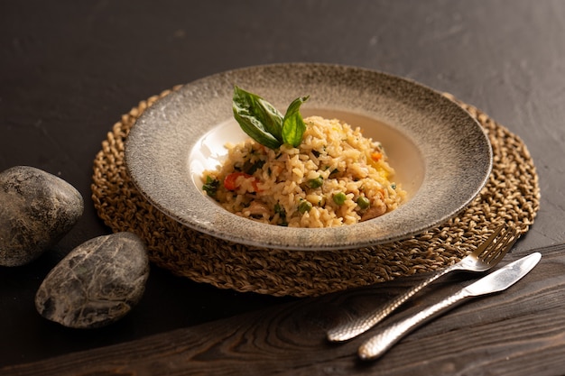 Risotto with chicken and vegetables, garnished with basil leaves, are beautifully preserved by cutlery.