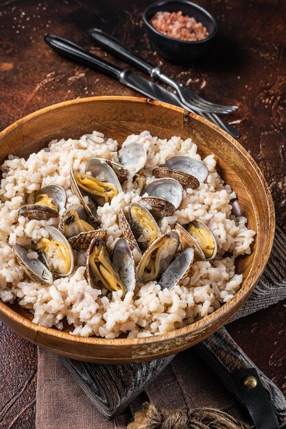 Risotto with clams and seafood in a wooden plate Dark backgroud Top view