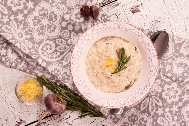 Risotto with garlic, rosemary and thyme on white wooden table.