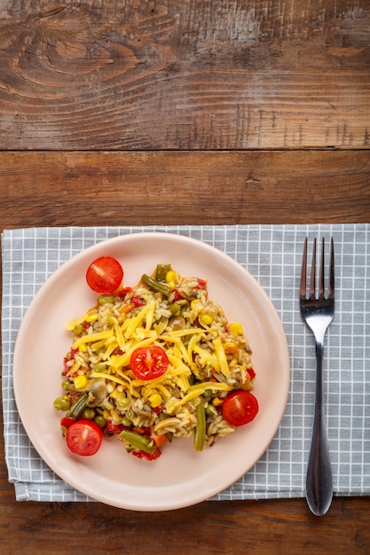 Risotto with mushrooms in a plate on a wooden background on a checkered napkin and fork.