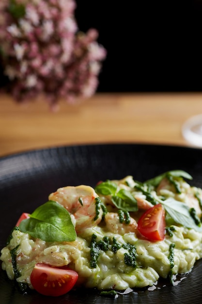 Foto risotto al pesto di basilico e pomodorini primo piano in banda nera su tavola di legno risotto su tavola di legno ristorante