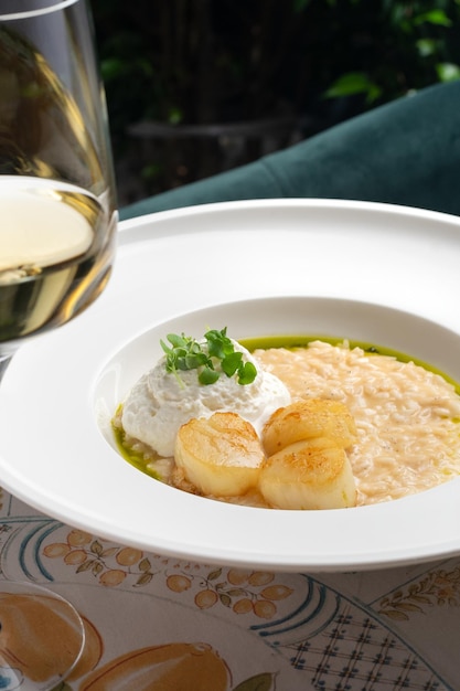 Risotto with scallops and truffle oil on white plate macro close up