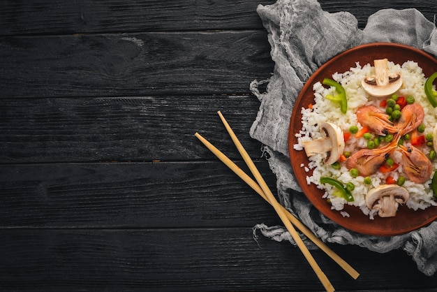 Ризотто с креветками и овощами Морепродукты Азиатская кухня На фоне деревянной текстуры Вид сверху Свободное пространство
