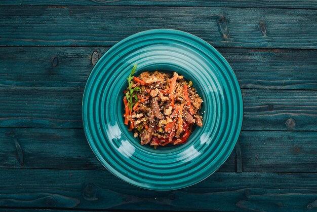 Risotto with veal and vegetables On a wooden background Chinese cuisine Top view Copy space