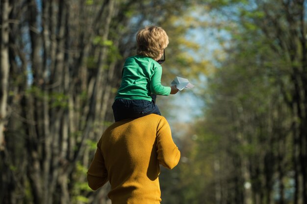 Rit op de rug. vader houdt zoontje op schouders en geeft kind meeliften in het park. ontspan je bent bij mij