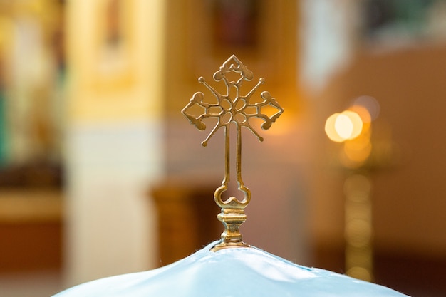 Rite van passage van het sacrament van de doop. foto van een mooi kruis op een lettertype voor baby's tegen een achtergrond van veel kaarslicht