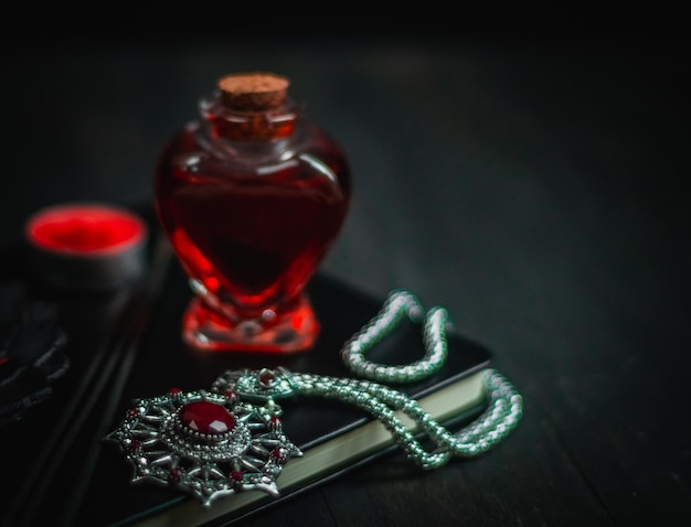 Ritueel amulet met rood stenen toverdrankboek en toverstokken op een zwarte achtergrond