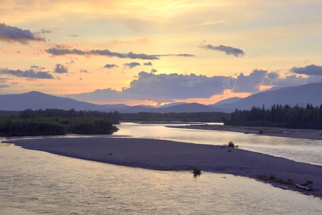 The river bank in the Altai mountains under the golden evening sky Siberia Russia