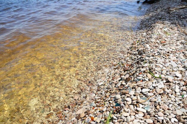 river bank with clear water and multicolored stones isolated copy space