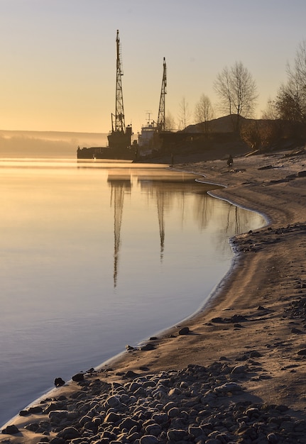 Photo river bank with cranes at dawn the bend of the coastline cranes in the distance