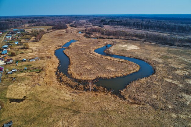 River bend in the shape of a horseshoe. The view from a great height. Early spring, landscape with dead grass.