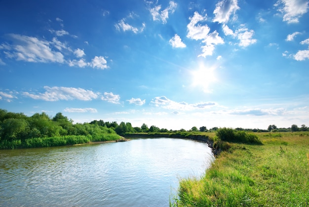 River flowing through fields with green grass