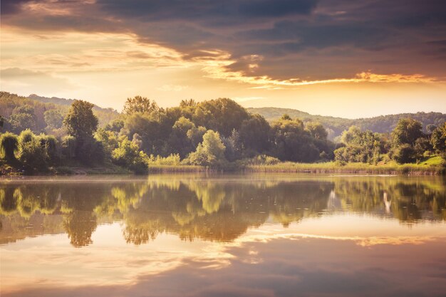 River and forest at sunset. Display trees and clouds in the water of the lake