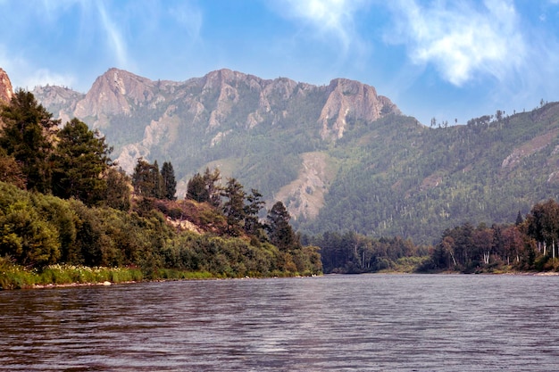 A river and forested mountains along its banks. Summer landscape, beauty of nature.