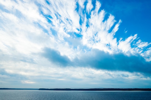 川の風景。穏やかな水と雲のある美しい青い空。木は最も近い海岸に生えています。コピースペースがあります