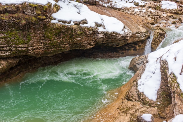 Fiume in montagna. zona montuosa. foto su una lunga esposizione, giornata nuvolosa. cascate in montagna nella foresta, paesaggio invernale di fiumi di montagna