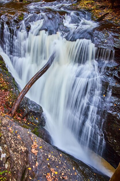 Photo river rages down steep gorge into rocks with fall leaves