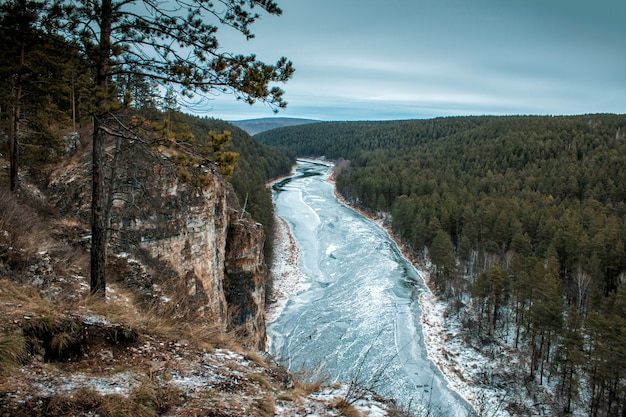 Fiume e costa rocciosa nella taiga in inverno