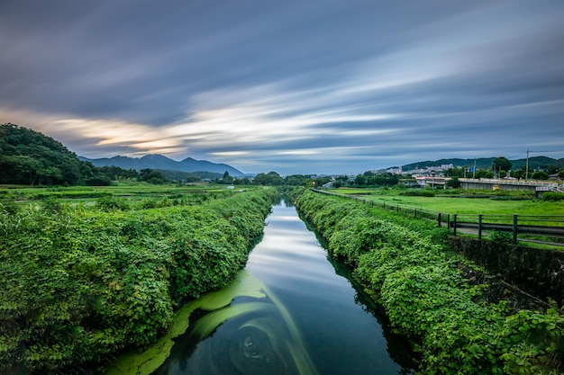 A river runs through a field with mountains in the background.