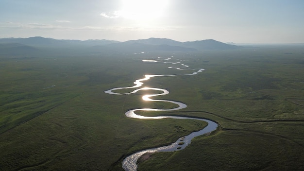 Foto un fiume scorre attraverso una pianura erbosa con montagne sullo sfondo.