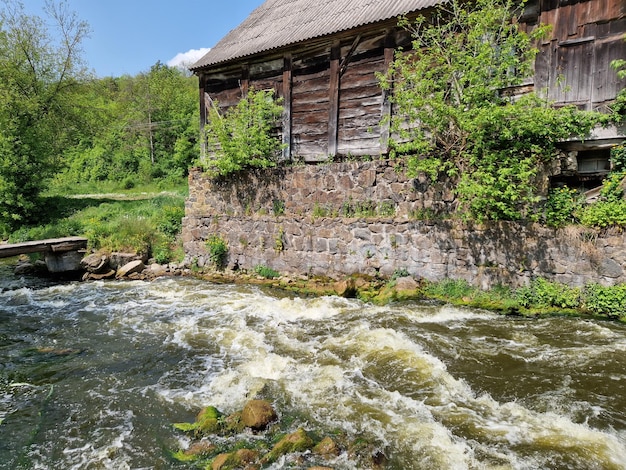 A river runs through a village with a wooden building and a wooden roof.