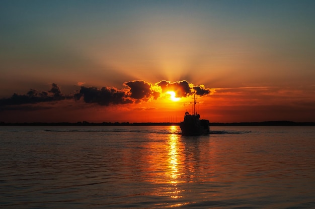 River at sunset with a small boat Cloudy sky and sunset reflection on the water