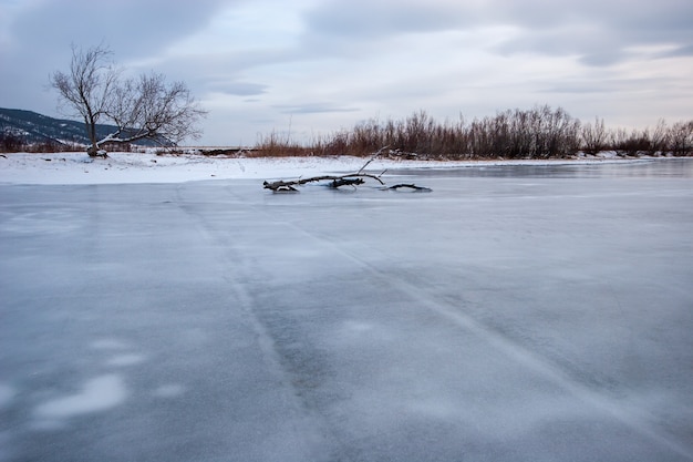 Фото Река с замерзшей водой и старыми следами от машины