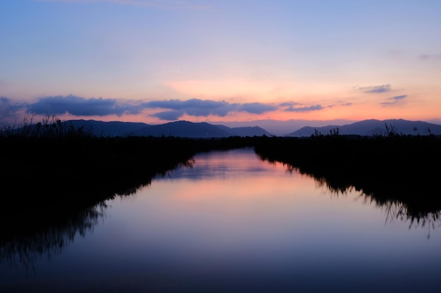 Photo a river with a pink sky and the sun is setting.