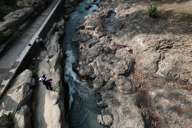 岩とその上を歩く人がいる川 川岸の凍った火山岩