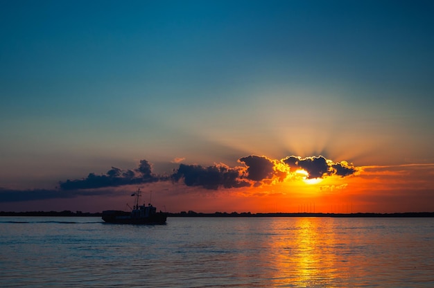 Rivier bij zonsondergang met een kleine boot Bewolkte lucht en zonsondergang reflectie op het water