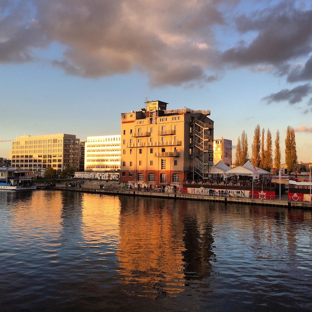 Rivier door gebouw tegen bewolkte lucht