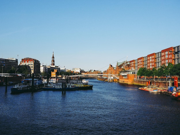 Rivier te midden van gebouwen tegen een heldere blauwe lucht bij zonsondergang