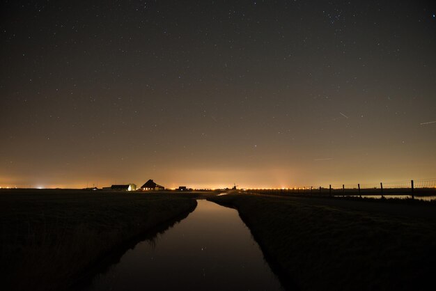 Rivier te midden van silhouet veld tegen de hemel in de schemering