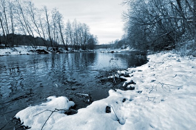 Foto rivier zonder ijs in de winter met sneeuw op de wal