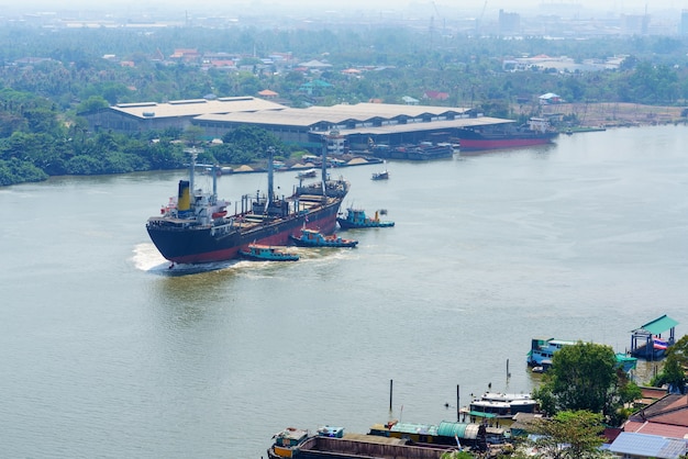 Riviersleepboten die containerschip in het midden van de Chao Phraya-rivier duwen