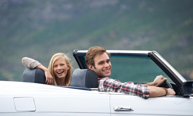 On the road to adventure A young couple driving in a convertible on a road trip