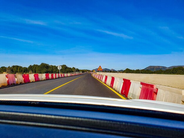 Road against blue sky seen through car windshield