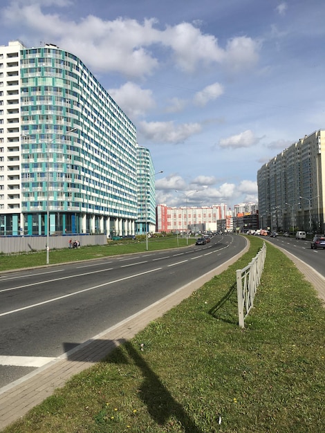 Road along city buildings with blue sky and clouds